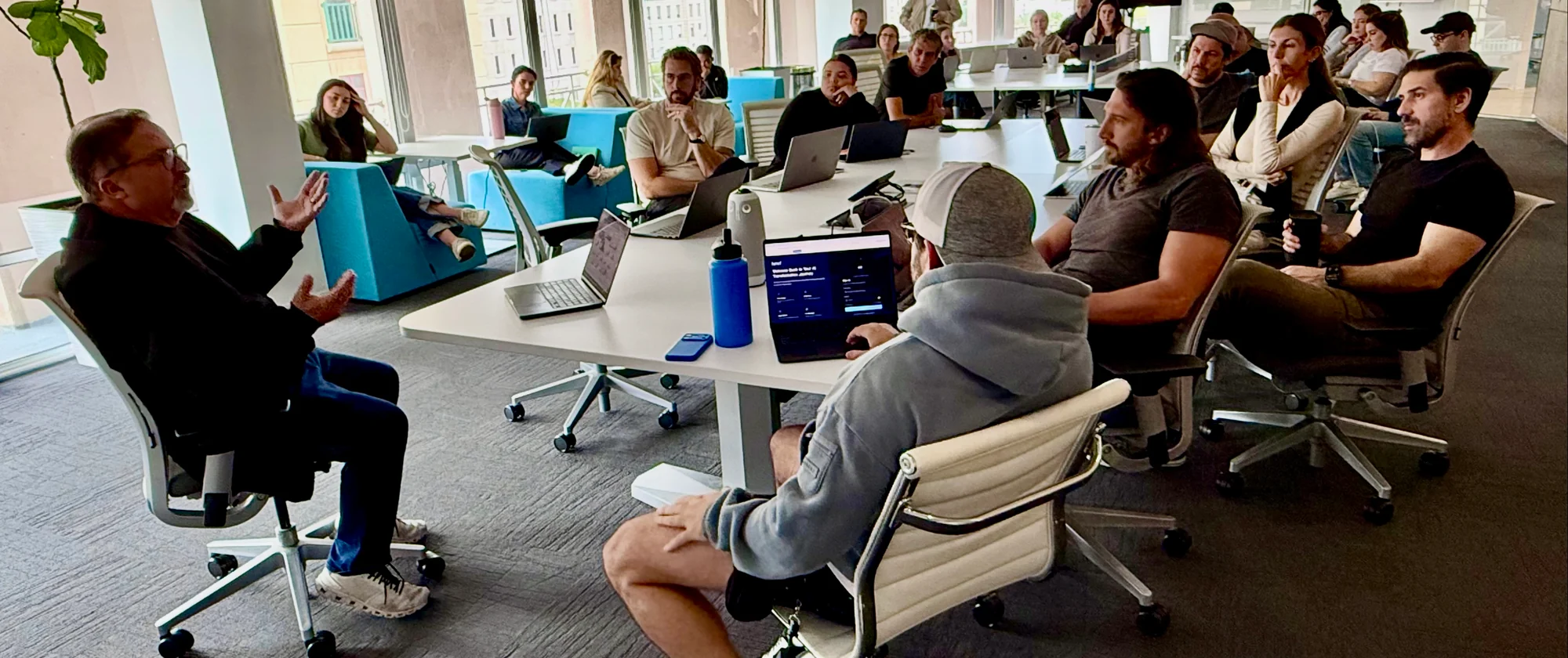 GlueIQ team discussing ideas around tables with open laptops.