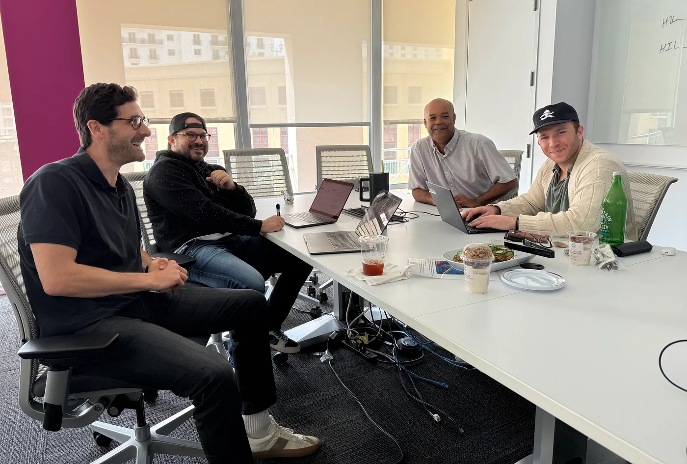 Four people gathered around a table with open laptops.